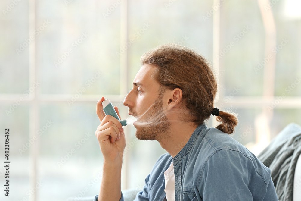 Man with allergy using asthma inhaler at home Man with allergy using asthma inhaler at home