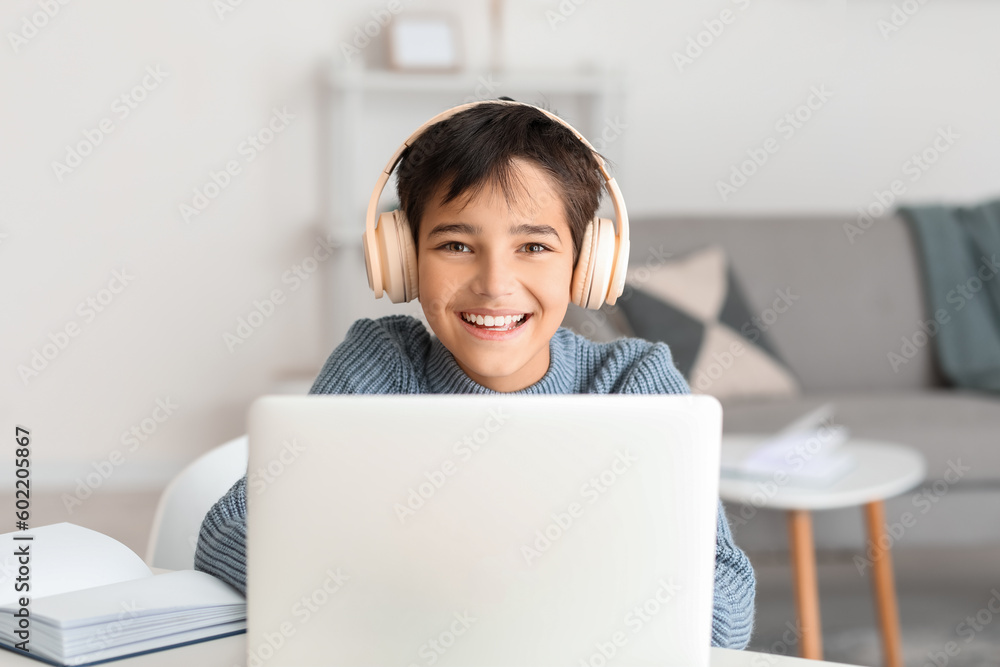 Happy little boy in headphones using laptop at home Happy little boy in headphones using laptop at home