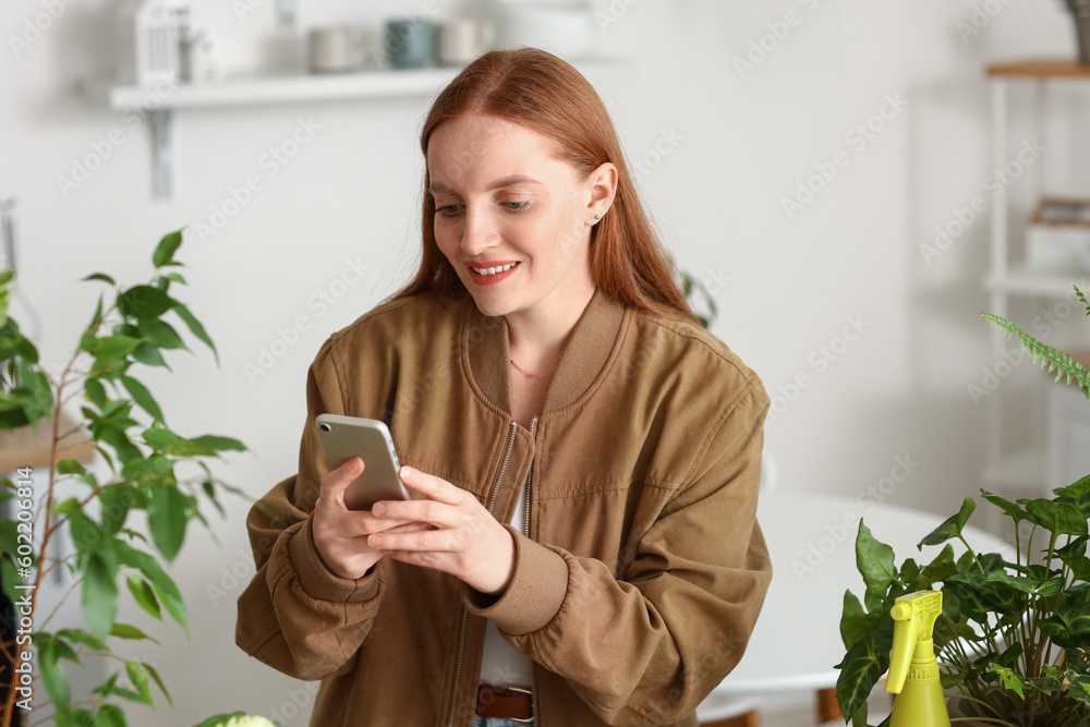 Young woman with green houseplants using mobile phone at home Young woman with green houseplants using mobile phone at home