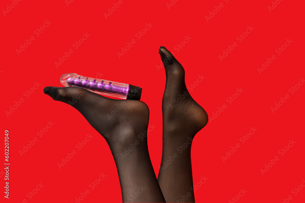 Female legs in stockings with vibrator on red background, closeup Female legs in stockings with vibrator on red background, closeup