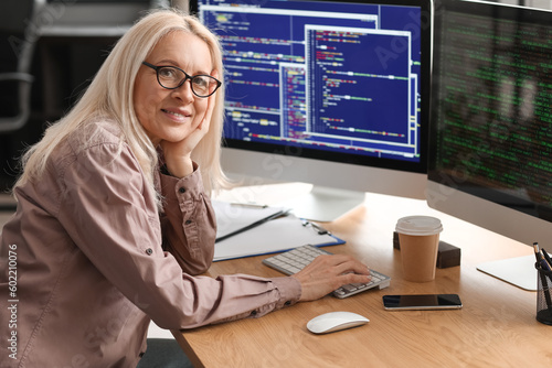 Konstfotografi Mature female programmer working with computer at table in office