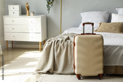 Big suitcase near bed in light room