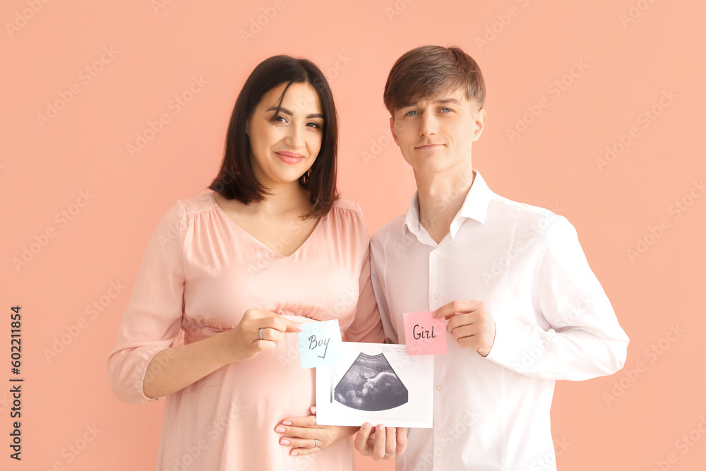 Young pregnant couple holding sonogram image and papers with sex of baby on pink background Young pregnant couple holding sonogram image and papers with sex of baby on pink background
