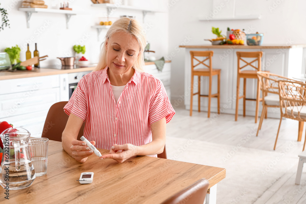 Mature diabetic woman measuring blood sugar level with lancet pen in kitchen Mature diabetic woman measuring blood sugar level with lancet pen in kitchen