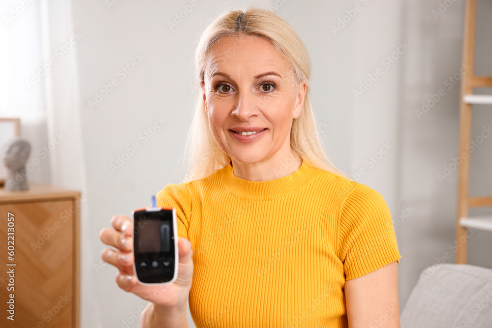 Mature diabetic woman with glucometer at home Mature diabetic woman with glucometer at home
