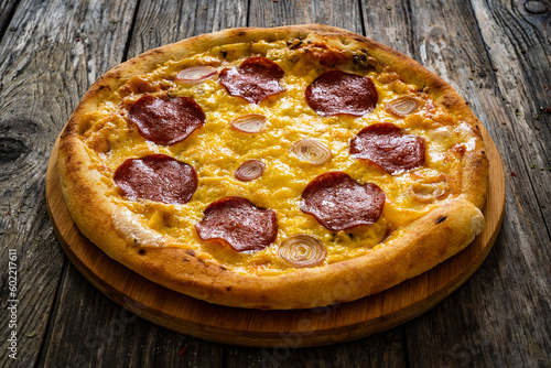 Circle pepperoni pizza with mozzarella cheese and onion on wooden table 