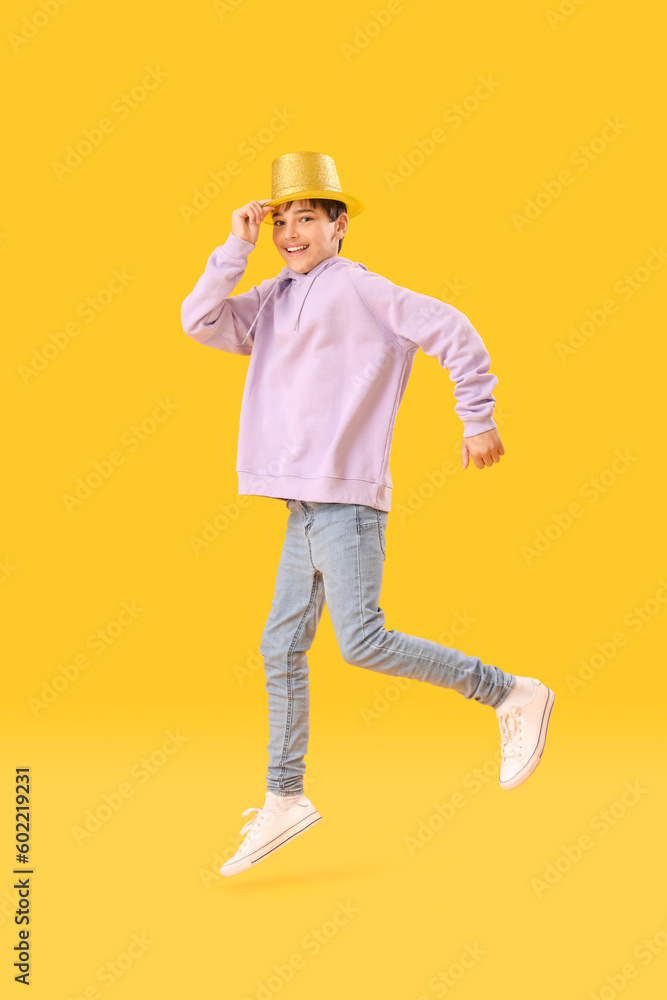 Little boy in party hat jumping on yellow background. Children's Day celebration Little boy in party hat jumping on yellow background. Children's Day celebration