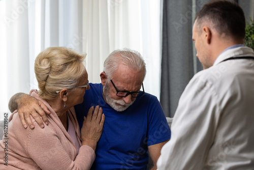 Distressed worried senior couple talking to doctor during bad medical result explanation photo