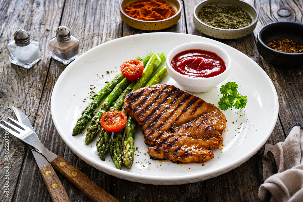 Barbecued meat and asparagus on wooden table Barbecued meat and asparagus on wooden table