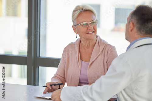 Senior woman filling insurance or other legal document at appointment with doctor. Elderly patient signing medical treatment contract, agreement form for medical care service, consultation, therapy