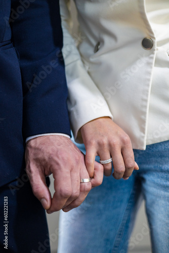 Chic jewelry boutique filled with opulent treasures, an engaged couple delicately intertwine their fingers, proudly displaying glistening diamond rings that catch the light. Loving couple.