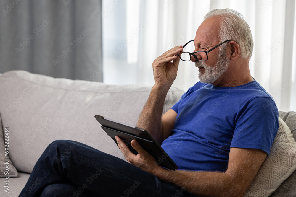 © Space_Cat - Senior man with glasses using digital tablet computer at home and having eyestrain or suffering from astigmatism and bad vision. Eyesight problems concept.