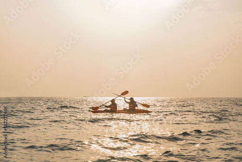 Man kayaking at sunset sea, kayaking, canoeing, boating. Man playing on the beach with kayak at the day time. People having fun outdoors. Concept of summer vacation .