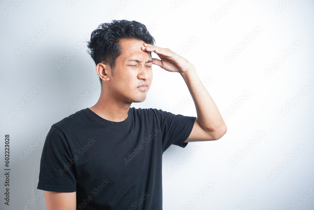 Asian Man wearing black t shirt touching his forehead in pain Asian Man wearing black t shirt touching his forehead in pain