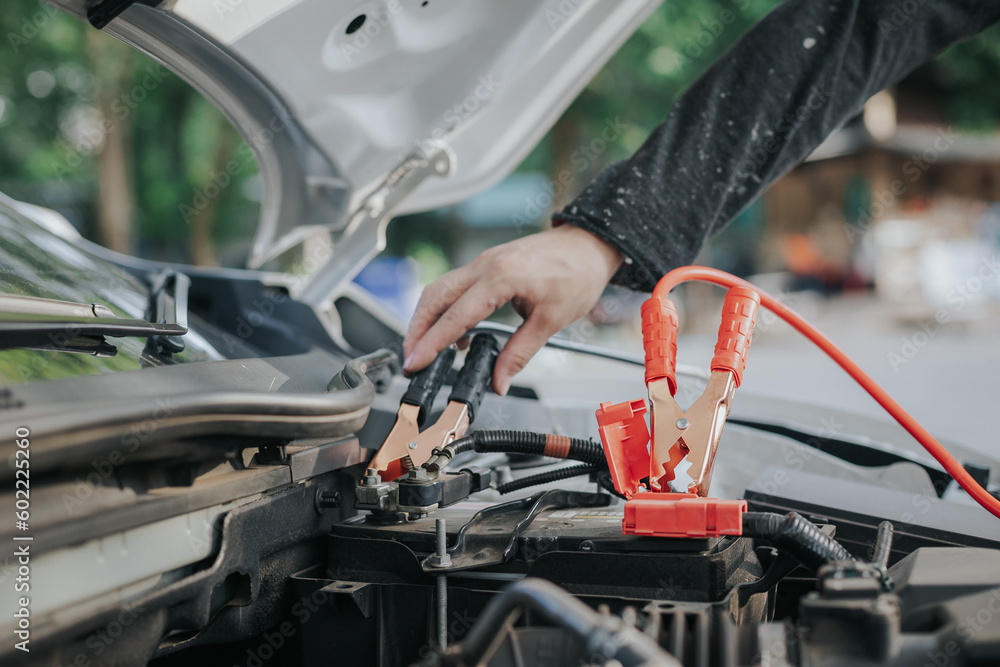 Close-up of auto mechanic charging car battery with electric rail jumper cables Close-up of auto mechanic charging car battery with electric rail jumper cables