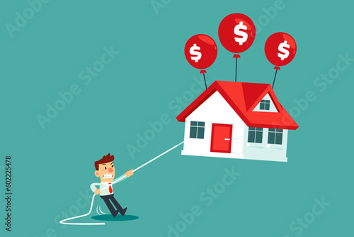 businessman holding rope tie to floating house with dollar sign balloon