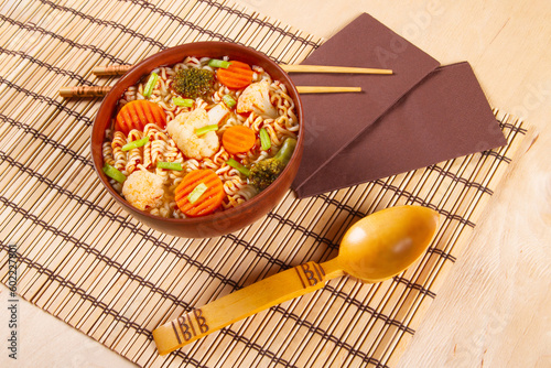 Traditional Asian instant noodles meal with vegetables on wooden background photo