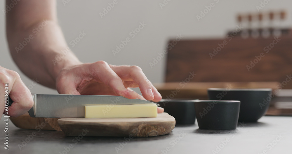 Obraz premium man cutting hard cheese with knife on wood board