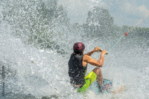 Photography Wakeboarding is a water sport in which the rider, standing on a wakeboard, is towed behind a motorboat across its wake and especially up off the crest in order to perform aerial maneuvers