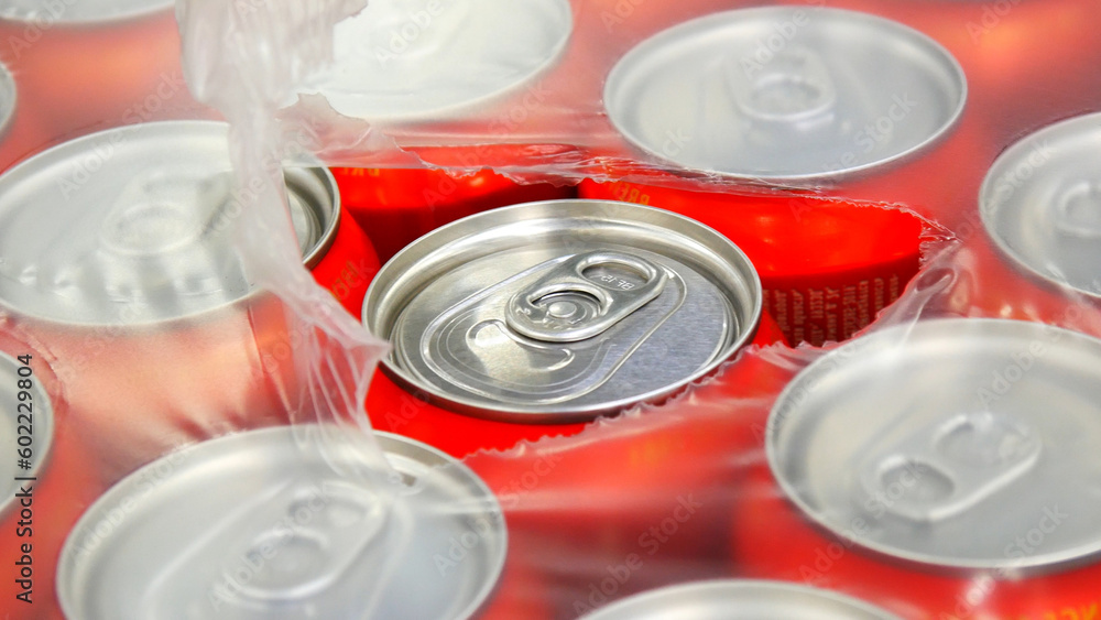 Close-up of many red cans of beer in plastic packaging torn from the top Close-up of many red cans of beer in plastic packaging torn from the top
