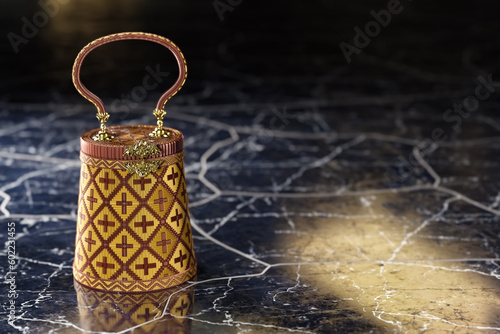 The bell-shaped Yan Lipao purse, a traditional Thai handcraft, is depicted in 3D illustration on a black marble backdrop.