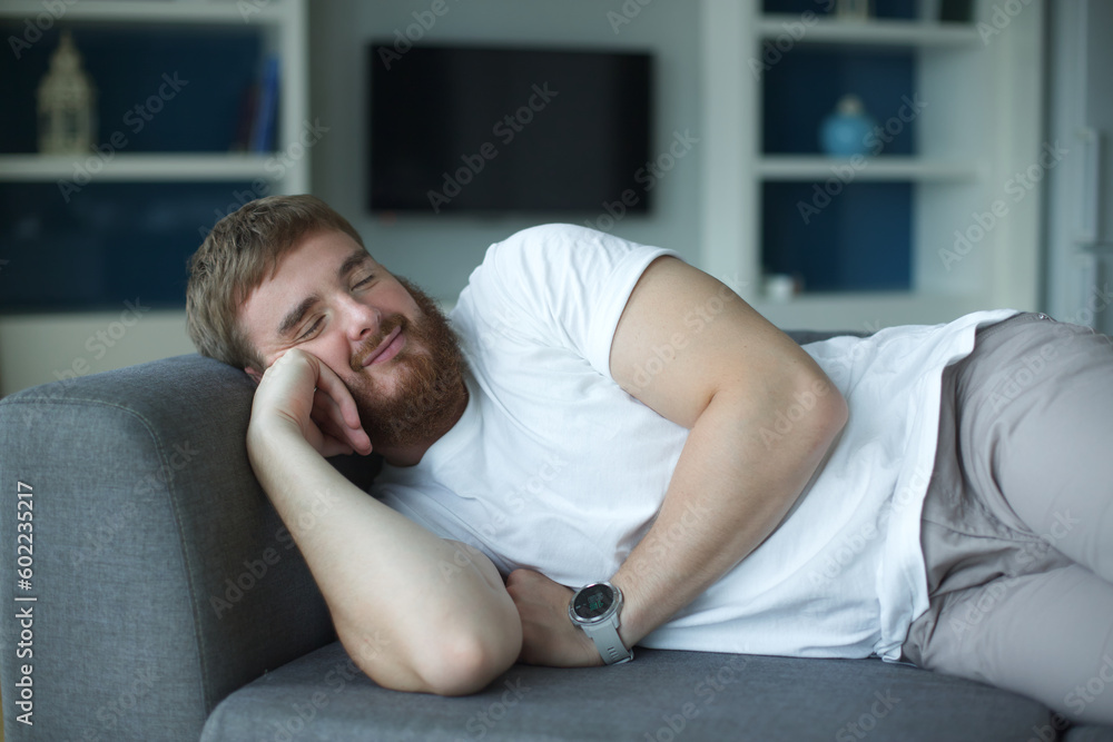 Sweet dreams. Serene millennial male lie on soft cozy couch in comfortable pose having tight sleep. Satisfied young guy nap on sofa at home enjoy good rest relax, man at living room at home Sweet dreams. Serene millennial male lie on soft cozy couch in comfortable pose having tight sleep. Satisfied young guy nap on sofa at home enjoy good rest relax, man at living room at home