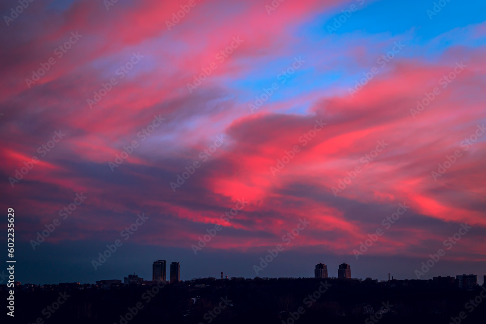 Sky over city at night with red dramatic clouds.