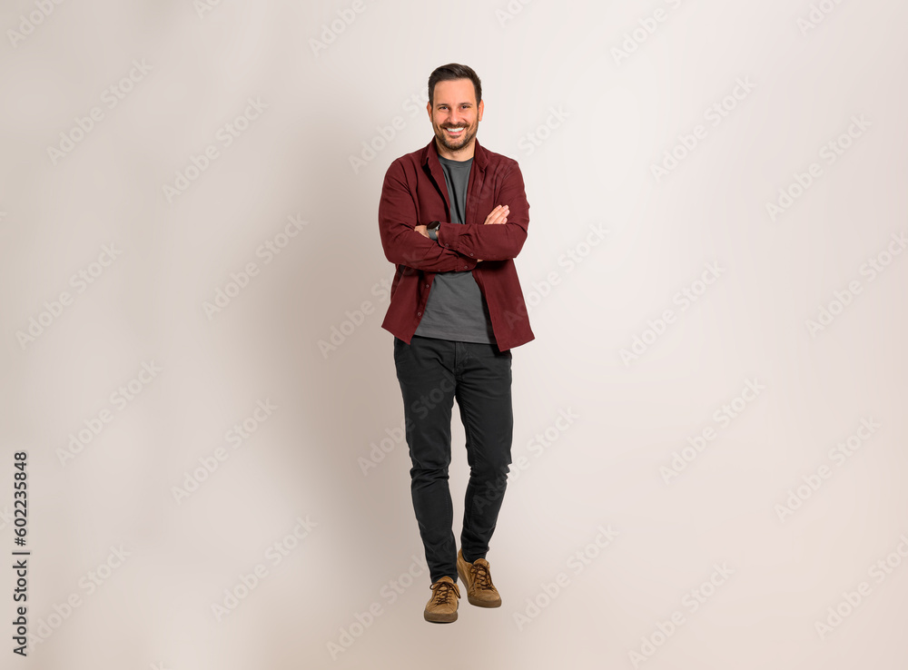 Portrait of happy young businessman with arms crossed posing confidently against isolated background. Handsome male entrepreneur dressed in maroon shirt smiling and looking at camera Portrait of happy young businessman with arms crossed posing confidently against isolated background. Handsome male entrepreneur dressed in maroon shirt smiling and looking at camera