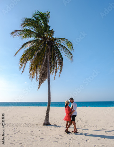 Eagle Beach Aruba, Palm Trees on the shoreline of Eagle Beach in Aruba, a couple of men, and a woman on the beach of Aruba
