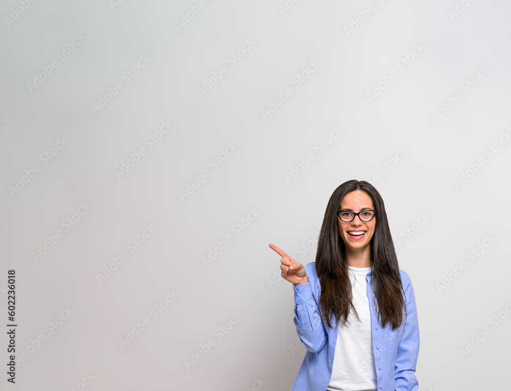 Portrait of cheerful female entrepreneur pointing towards copy space while standing isolated on background. Businesswoman smiling and doing advertisement while looking at camera Portrait of cheerful female entrepreneur pointing towards copy space while standing isolated on background. Businesswoman smiling and doing advertisement while looking at camera