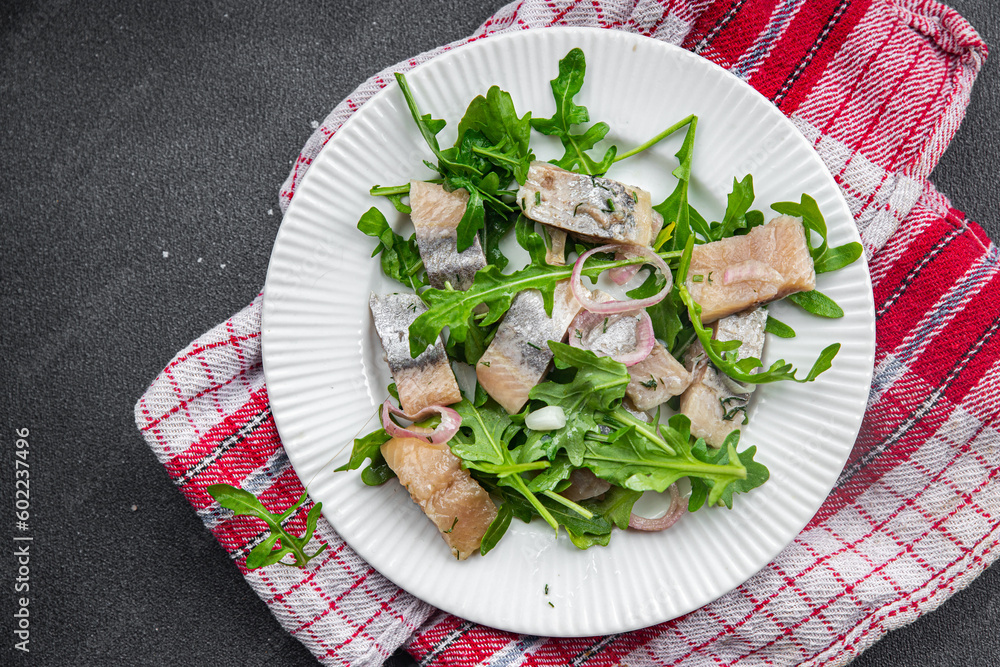 herring pieces pickled onion, green arugula leaves meal food snack on the table copy space food background rustic top view  pescatarian diet