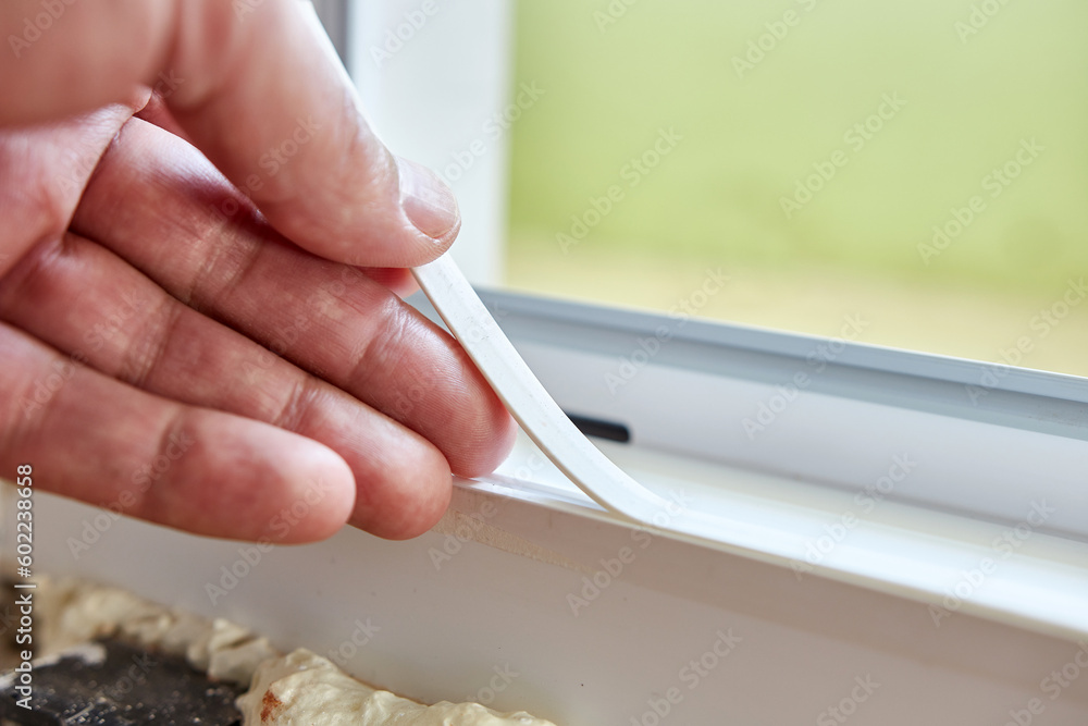 Obraz premium A seal is attached to the plastic door frame. Maintenance of metal-plastic structures. Energy-saving construction technologies.