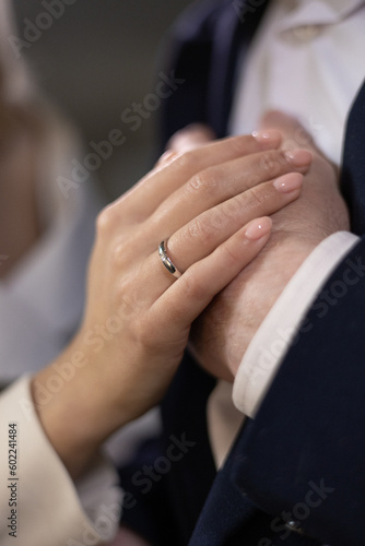 Girl holds hand on her partner s hand  pointing to their wedding rings in a close-up shot. Moment of emotional connection and unity. Focus is on details of hands  wedding rings  symbolizing love.