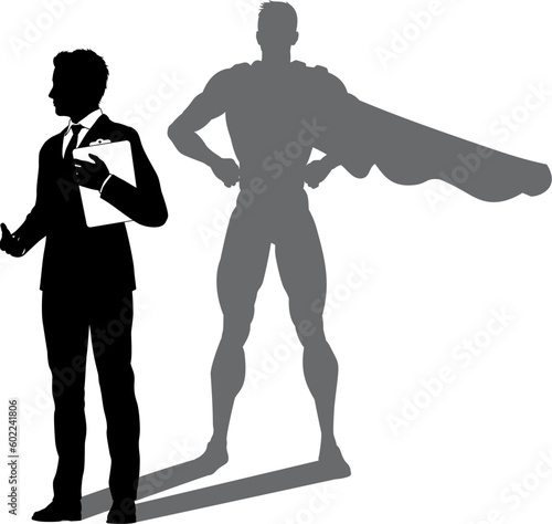 A superhero business man revealed by his shadow silhouette as a super hero in a cape
