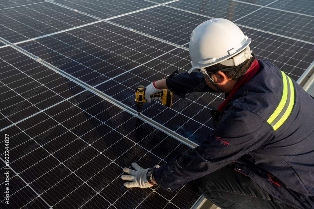 © tong2530 - A Technicians power drill to install solar panels on the new roof of the factory. Solar power or Clean energy concept.