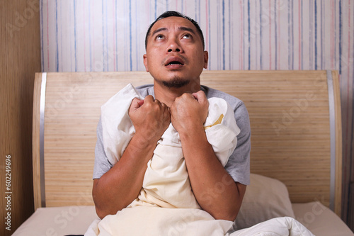фотографія Asian man sitting in bed stressed and scared suffering from nightmare and horror