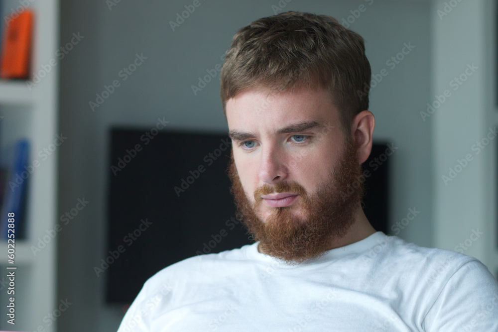 Portrait young european beard pensive thoughtful relaxed lonely guy, man is dreaming, thinking, relax at home in living room at comfortable sofa, couch with his hands behind head Portrait young european beard pensive thoughtful relaxed lonely guy, man is dreaming, thinking, relax at home in living room at comfortable sofa, couch with his hands behind head