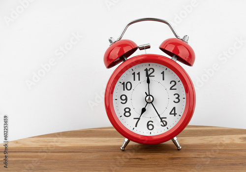 Red alarm clock on grey wall background