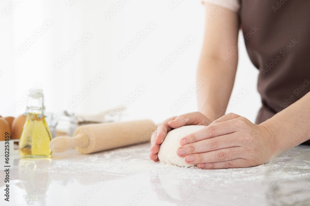 Female hands kneading dough, baking background. Cooking ingredients eggs, flour, milk, rolling pin on white style kitchen.  Copy space.