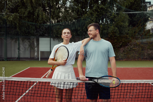 Happy Couple, tennis and sport portrait, training and exercise together outdoor, posing at tennis net on court.