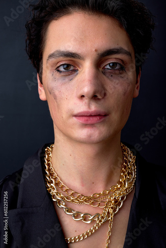 crying caucasian man dressed in black shirt, posing at camera with mascara smudged from crying because of discrimination. Concept of diversity, transgender, lgbt. transvestite with chain, isolated photo