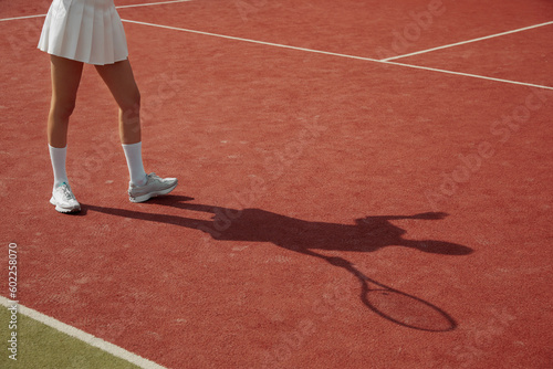 Player shadow on the tennis court carpet during the match. A woman play tennis professionally. Activity for recreation. Tennis player in action. © Davidovici