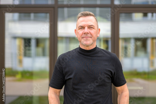 Man with gray hair in front of a glass office building