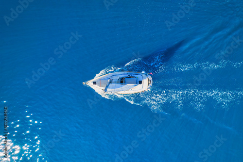 Wave and sail yacht on the sea as a background. .Sea and waves from top view. Blue water background from top view. Top view from drone. Summertime vacation. Travel image