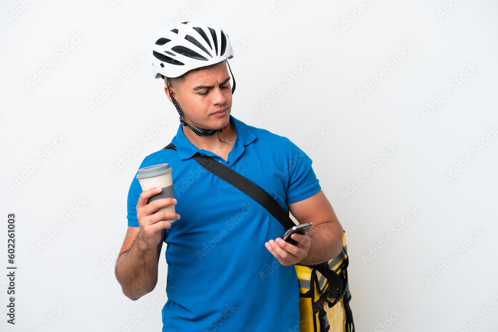Young caucasian man with thermal backpack isolated on white background holding coffee to take away and a mobile Young caucasian man with thermal backpack isolated on white background holding coffee to take away and a mobile