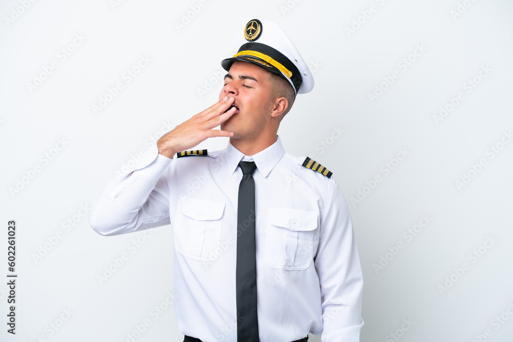 Airplane pilot caucasian man isolated on white background yawning and covering wide open mouth with hand Airplane pilot caucasian man isolated on white background yawning and covering wide open mouth with hand