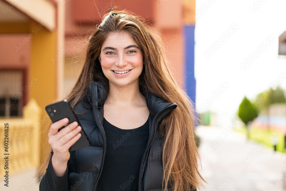 Young pretty caucasian woman using mobile phone at outdoors smiling a lot Young pretty caucasian woman using mobile phone at outdoors smiling a lot