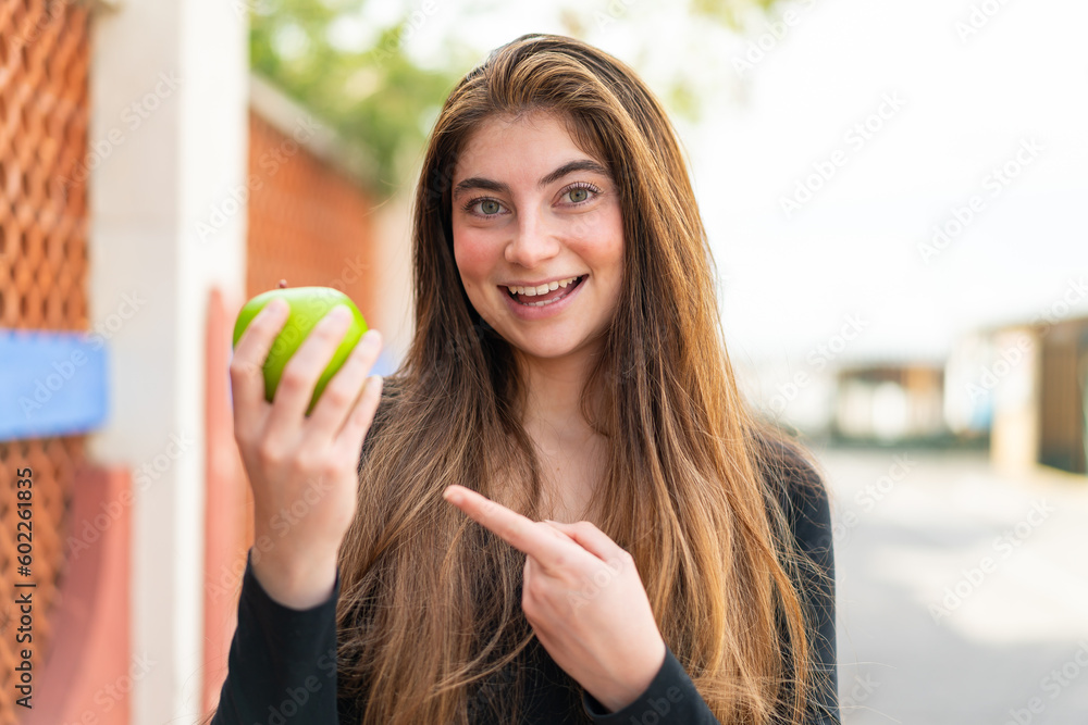 Young pretty caucasian woman with an apple at outdoors and pointing it Young pretty caucasian woman with an apple at outdoors and pointing it