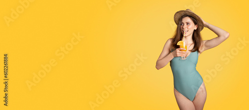 Happy lady in swimsuit and straw hat enjoying cocktail and looking aside at free space on yellow background, panorama © Prostock-studio