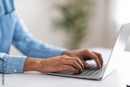 Unrecognizable Male Working With Laptop At Desk In Office